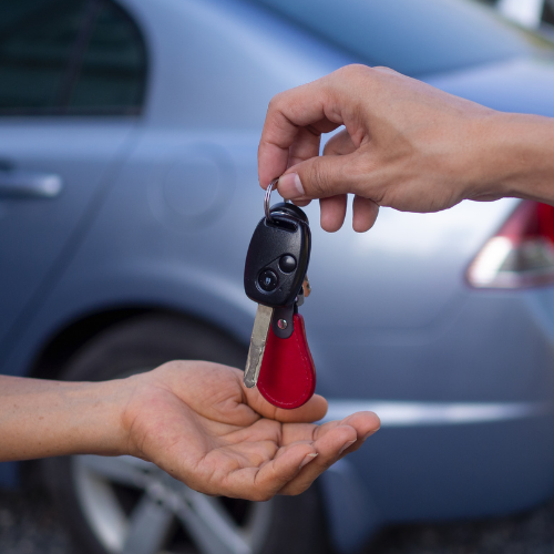 Man handing off car keys to new owner.
